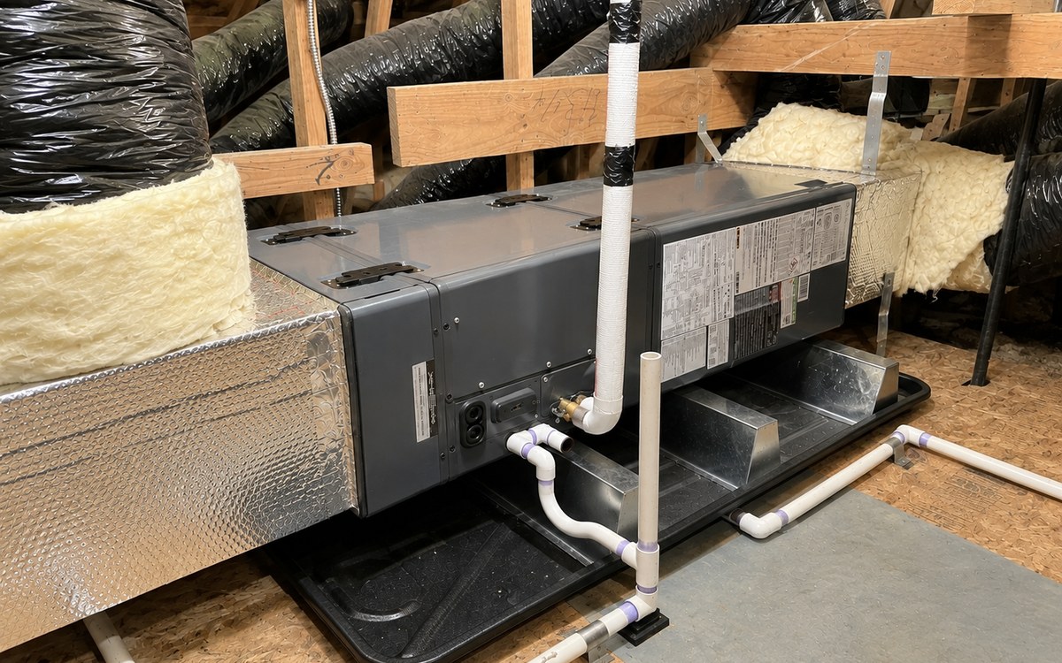Concealed ducted mini-split air handler installed in an attic, connected to insulated flex duct runs with condensate piping